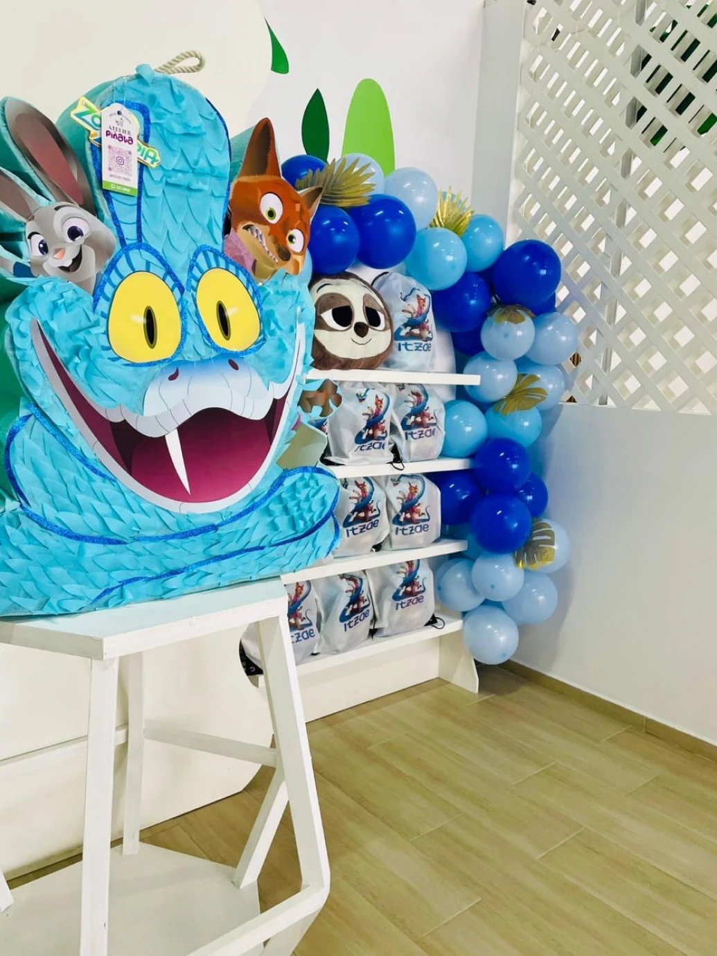 Piñata temática junto a la pared de dulceros y arco de globos azules