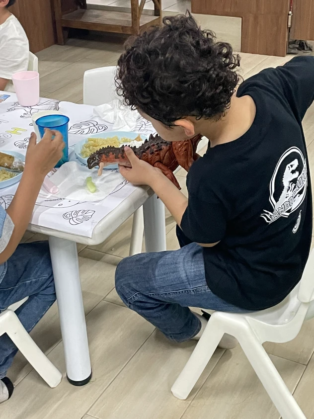Niños coloreando el mantel de dinosaurios durante la fiesta