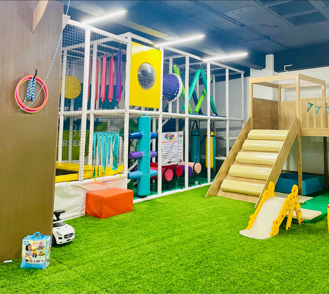 Área de juegos con escaleras, resbaladilla y pasto